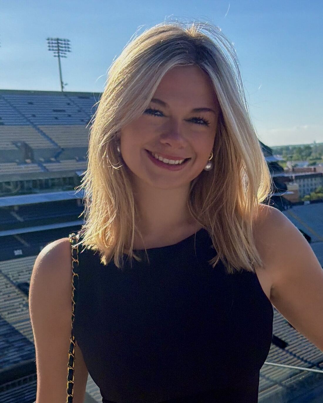 Headshot of Sofie Finnerty smiling, with Tiger Stadium behind her